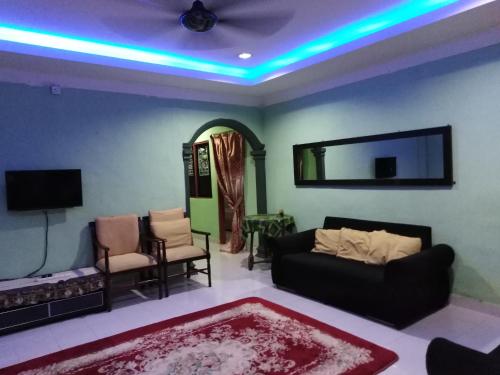 een woonkamer met een bank en een tv bij Adeeva Homestay Langkawi in Pantai Cenang
