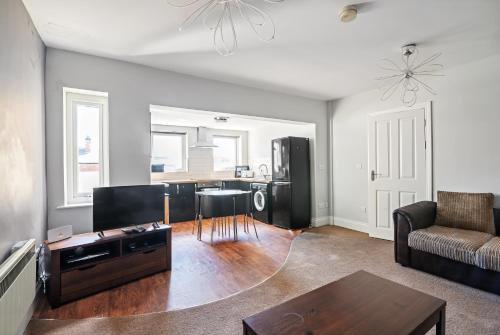 a living room with a couch and a table at Weatherhead Lodge - Modern and Sleek Derby Apartment in Derby