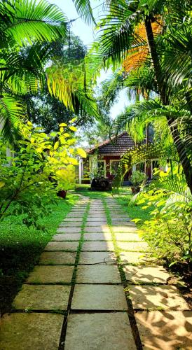 a stone path in front of a house with palm trees at Garden Villa in Vagator
