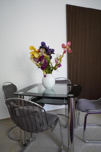 a vase of flowers on a glass table with chairs at Cafe Alice & Pension GmbH in Potsdam