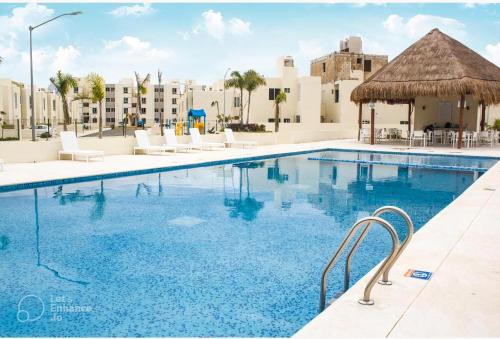 a swimming pool at a resort with chairs and a thatch roof at Casa Girasol Tulum in Tulum