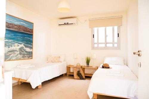 1 dormitorio con 2 camas y un cuadro en la pared en רגע ערבה en ‘En Yahav