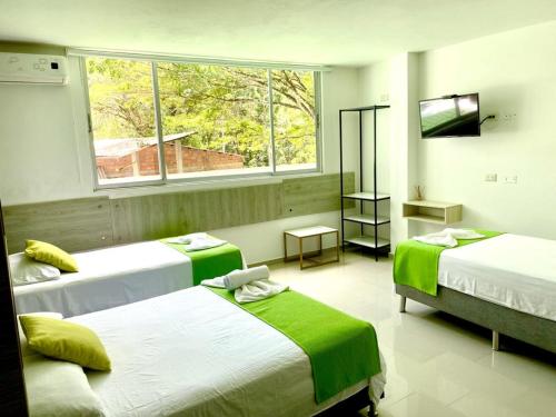 a bedroom with three beds and a window at Biohotel Rio Claro in Doradal