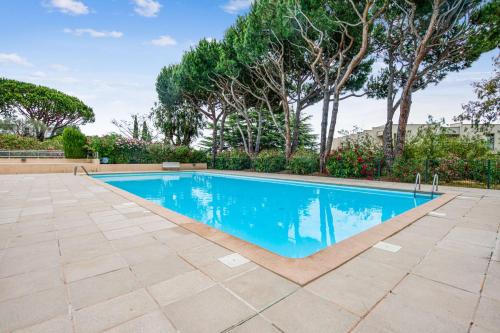 a swimming pool in a yard with trees at Appartement Bréguières - Welkeys in Antibes