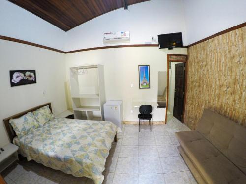sypialnia z łóżkiem, kanapą i telewizorem w obiekcie Casa de temporada Refugio das Aguias w mieście Ubatuba