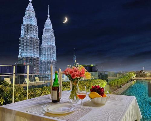 uma mesa com uma garrafa de vinho e um vaso de flores em Like Home Star KLCC em Kuala Lumpur