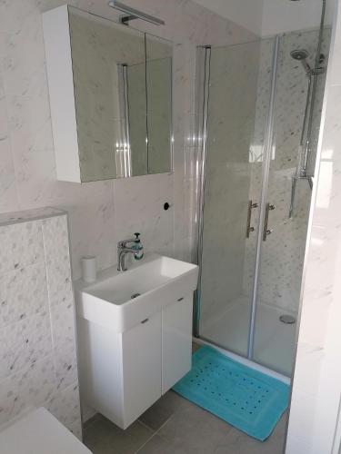 ein weißes Bad mit einem Waschbecken und einer Dusche in der Unterkunft Galeb in Rijeka