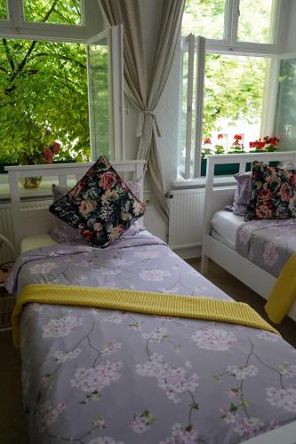 two beds in a room with two windows at Cafe Alice & Pension GmbH in Potsdam