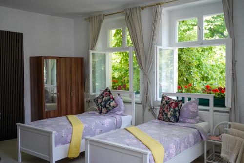 1 dormitorio con 2 camas y 2 ventanas en Cafe Alice & Pension GmbH, en Potsdam