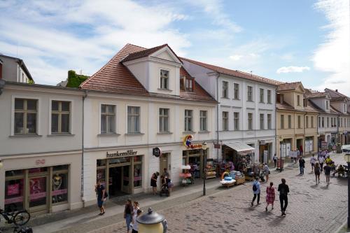 un grupo de personas caminando por una calle con edificios en Cafe Alice & Pension GmbH, en Potsdam