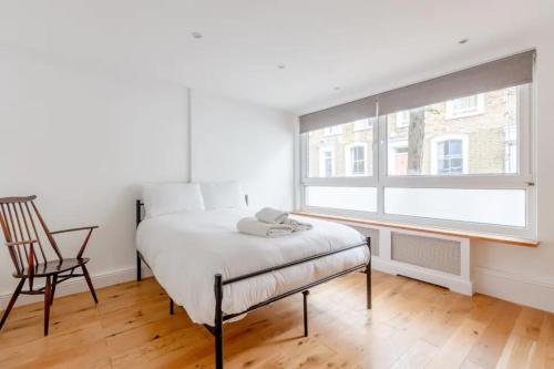 a bedroom with a bed and a chair and a window at Spacious 1 Bedroom Apartment in Vibrant Angel in London