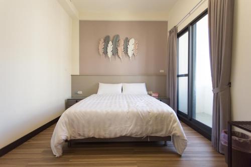 a bedroom with a white bed and a large window at 喜苑民宿 in Jinhu