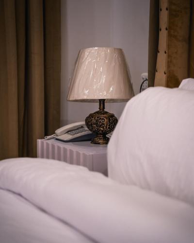 a lamp on a table next to a bed at ISLE OF HIGHLAND TOURS Guest House in Gilgit