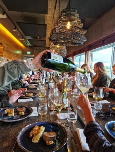 a person is pouring a glass of wine at a table at West Ranga lodge in Hella