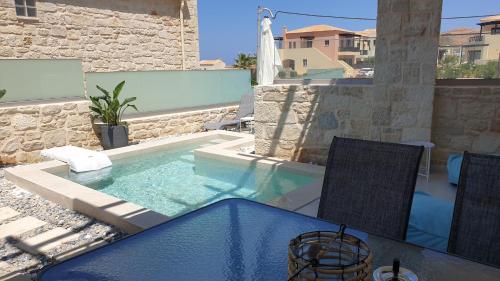 una piscina con mesa y sillas en un patio en Zefyros Suite , Seafront retreat !, en Panormos Rethymno
