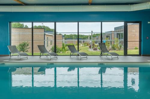 - une piscine avec des chaises, une table et de l'eau dans l'établissement The Originals City, Ax Hotel, La Châtaigneraie, à La Châtaigneraie