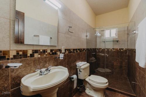 a bathroom with a sink and a toilet and a shower at Primavera Suites in Zihuatanejo