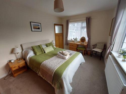een slaapkamer met een bed met een groene deken bij Private apartment, parking, sea and country views in Lyme Regis