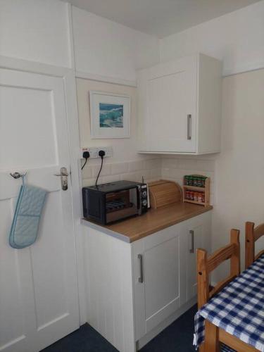 a kitchen with white cabinets and a microwave on a counter at Private apartment, parking, sea and country views in Lyme Regis