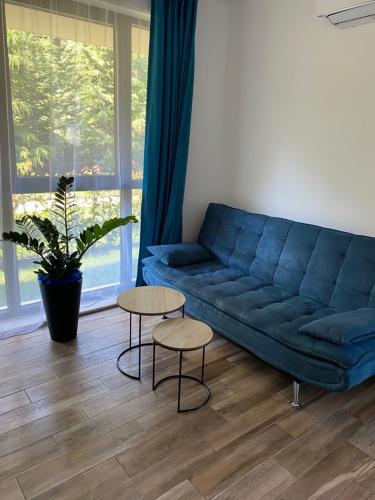 a living room with a blue couch and two tables at Studio PAMI in St. St. Constantine and Helena