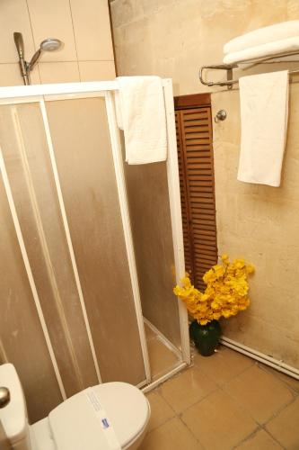 a bathroom with a shower with a toilet and yellow flowers at KALE EVİ BUTİK OTEL 