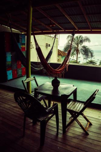 a hammock and a table and chairs on a porch at Hospedagem ocean view ilha g in Abraão