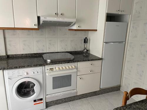 a kitchen with a refrigerator and a washer and dryer at Apartamento economico a 100m de la playa ESTANCIA MINIMA 4 NOCHES in A Pobra do Caramiñal
