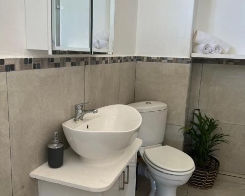 a bathroom with a white sink and a toilet at Ocean’s Edge in Umdloti