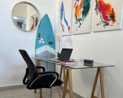 a desk with a laptop and a mirror and a surfboard at Ocean’s Edge in Umdloti
