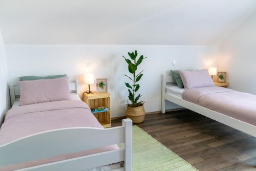 two beds in a room with white walls and wooden floors at Villa Cerkniško jezero in Cerknica