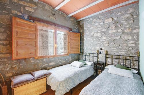1 dormitorio con 2 camas y pared de piedra en Can MartiPol, en La Pobla de Lillet