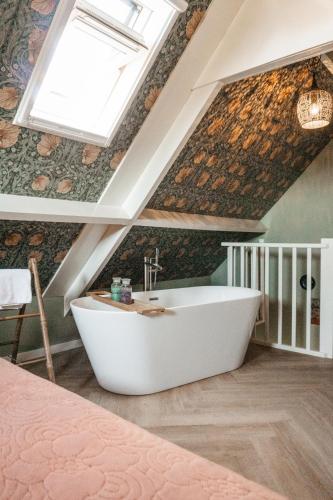 a bathroom with a white bath tub in the attic at Logement Cornelia - Tholen, Zeeland in Tholen