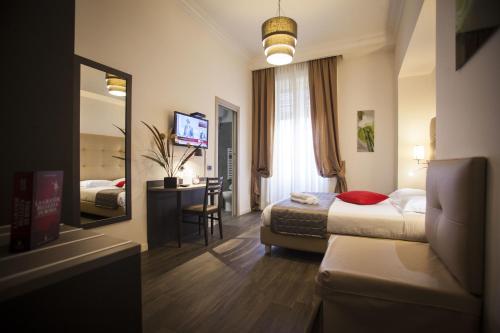 una camera d'albergo con letto, scrivania e specchio di Aventino Guest House a Roma