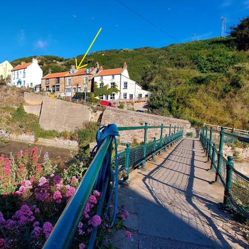 a bridge over a river with flowers on a hill at Sea Haven holiday cottage at Staithes in Staithes