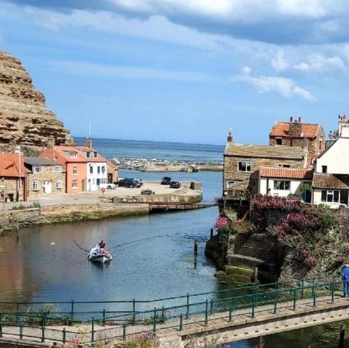 a person in a boat in a river near a town at Sea Haven holiday cottage at Staithes in Staithes