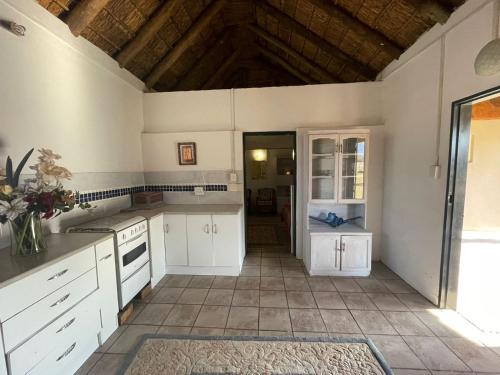 cocina con armarios blancos y suelo de baldosa en Vanross Self Catering Accommodation, en Thabazimbi