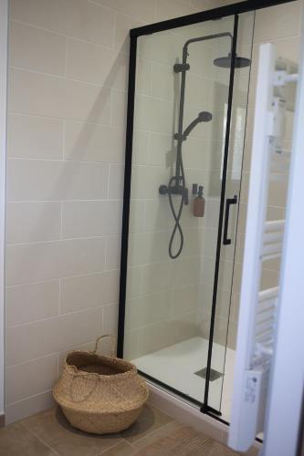 a glass shower in a bathroom with a basket at L'Embellie, maisonnette tout confort en pleine nature in Suze