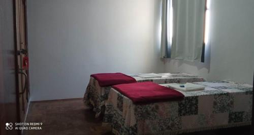 a room with two beds with red pillows at Casa do Juá 2 in Lavras