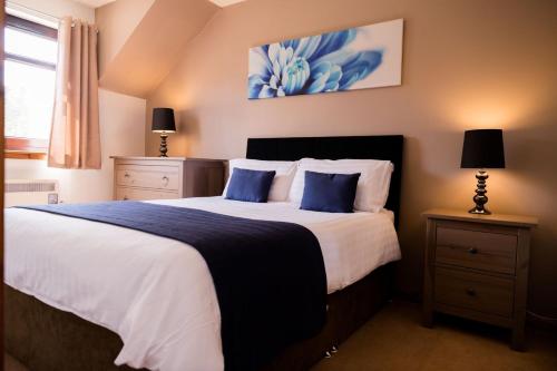 a bedroom with a large bed with blue pillows at The Galleries No 2 in Spean Bridge