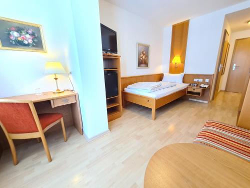 a hotel room with a bedroom with a desk and a bed at Thermenhotel Tannenhof - Ihr Wohlfühl-Hotel in Bad Füssing