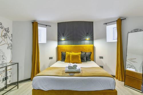 una camera da letto con un grande letto con cuscini gialli di Appartement - Château de Beuzeval - Welkeys a Houlgate