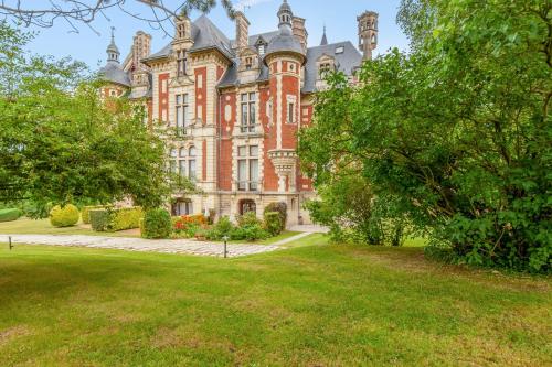 um grande edifício de tijolos vermelhos com árvores em frente em Wonderful apartment in a château with a yard - Houlgate - Welkeys em Houlgate