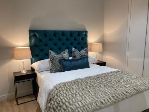 a bedroom with a large bed with a blue headboard at Luxury Apartment at Ellipse Waterfall, Midrand Near Mall of Africa in Midrand