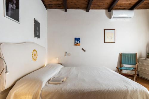 a bedroom with a white bed and a chair at Villetta sogno d'estate in Flumini di Quartu