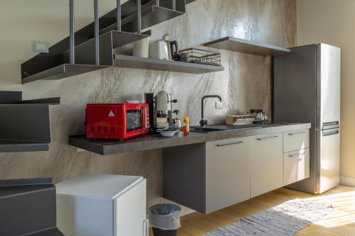 a kitchen with white cabinets and a red appliance on a shelf at B&B Margante in Somma Lombardo