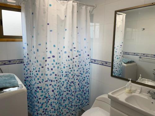 a bathroom with a shower curtain and a toilet at Casa de campo, con hermosa vista al mar in Tongoy