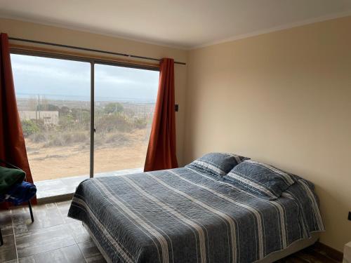 a bedroom with a bed and a large window at Casa de campo, con hermosa vista al mar in Tongoy