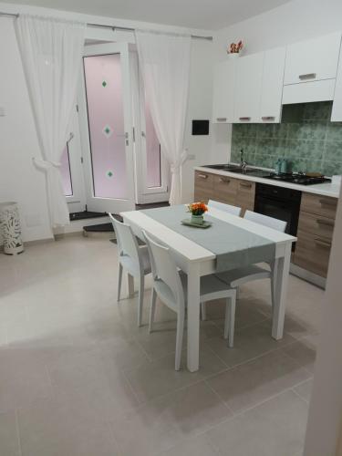 a white kitchen with a white table and chairs at Casetta Nilu' in Procida