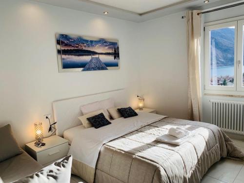 een witte slaapkamer met een bed en een raam bij Dolomia Gioele in Molveno