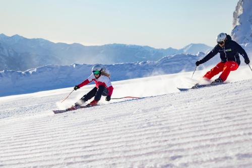 two people are skiing down a snow covered slope at das Bergerleben in Sonnenalpe Nassfeld